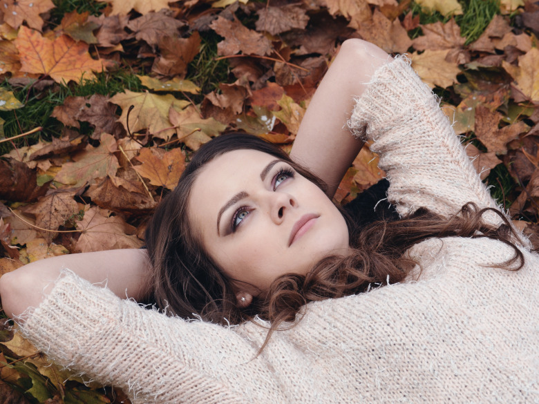 young woman thinking while laying in the leaves