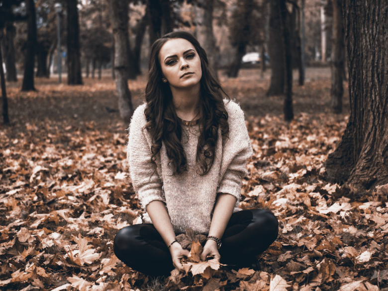 Young woman sitting in the leaves thinking of ways to get out of feeling stuck in life