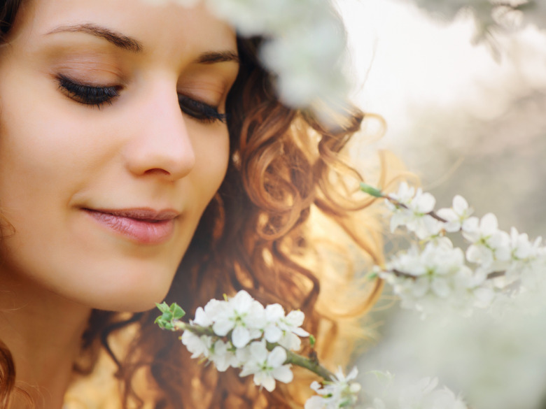 Woman with a sweet smile looking down at some pretty flowers