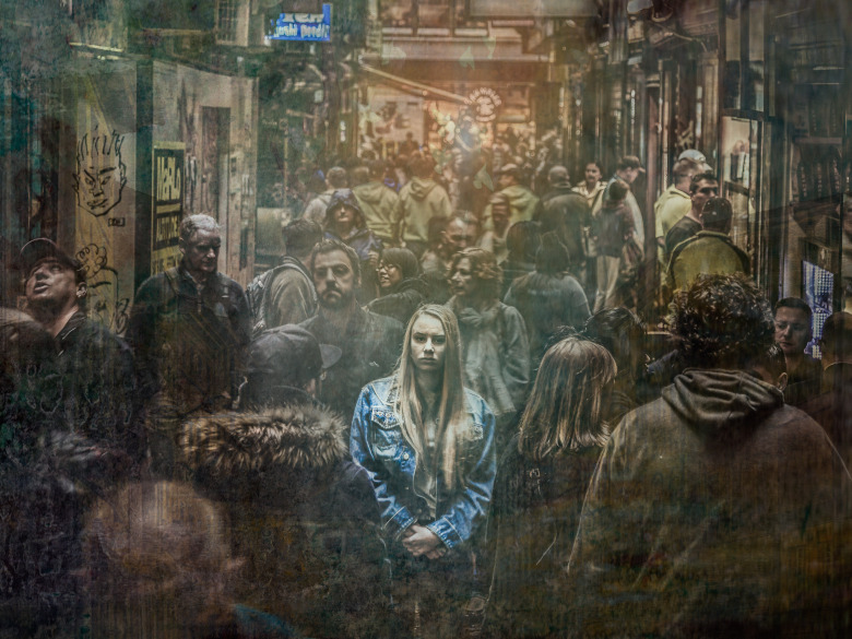 Woman in a crowd of people looking scared and overwhelmed