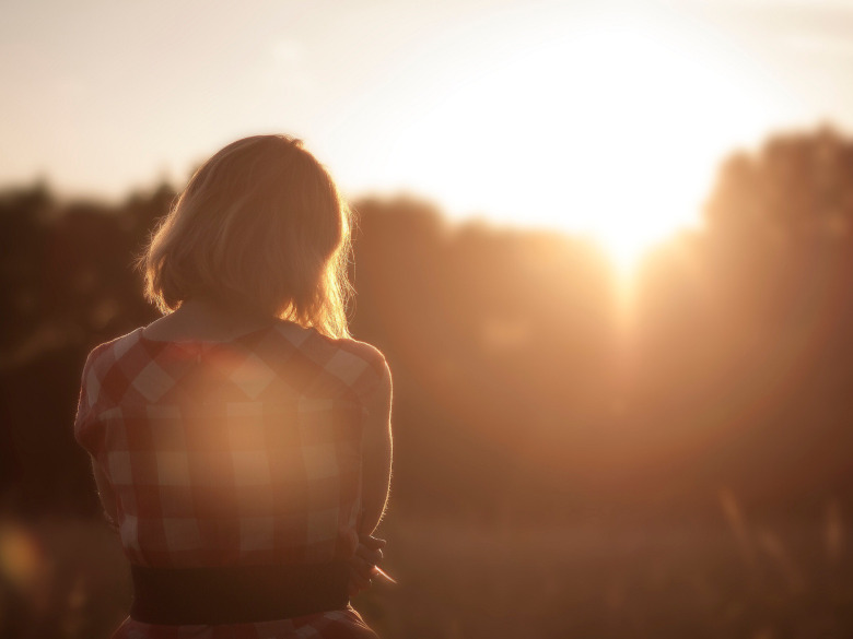 Woman peacefully daydreaming outdoors in sunlight