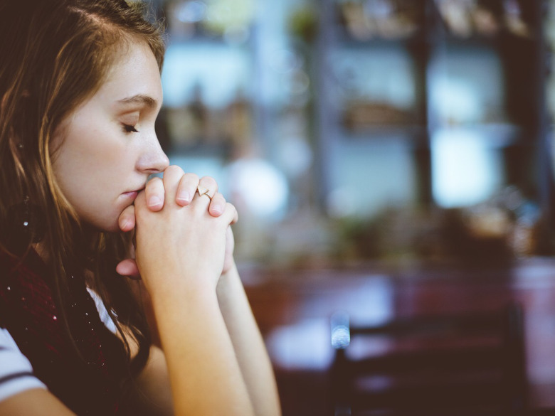 Daily spiritual practice. woman praying with her eyes closed and hands folded