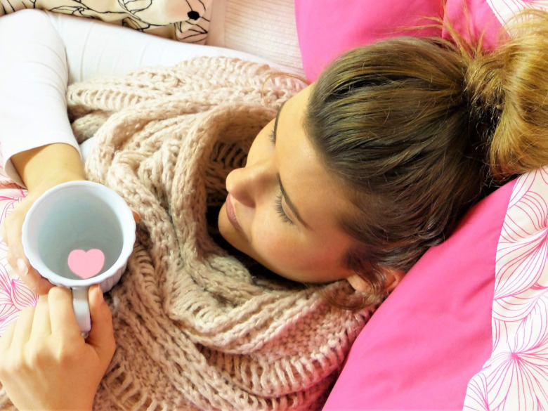 Young woman sitting in bed with cup of coffee feeling depressed