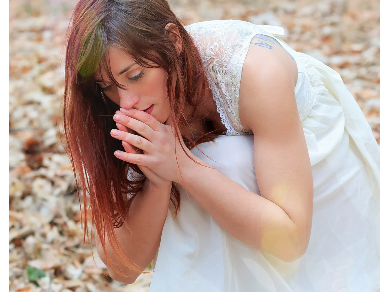 Young Woman with praying hands leaning forward