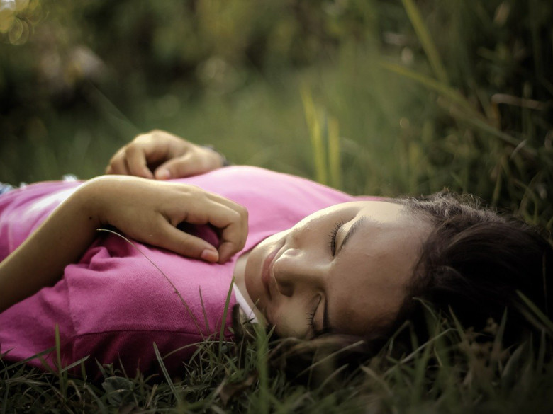 woman peacefully laying in the grass in the morning